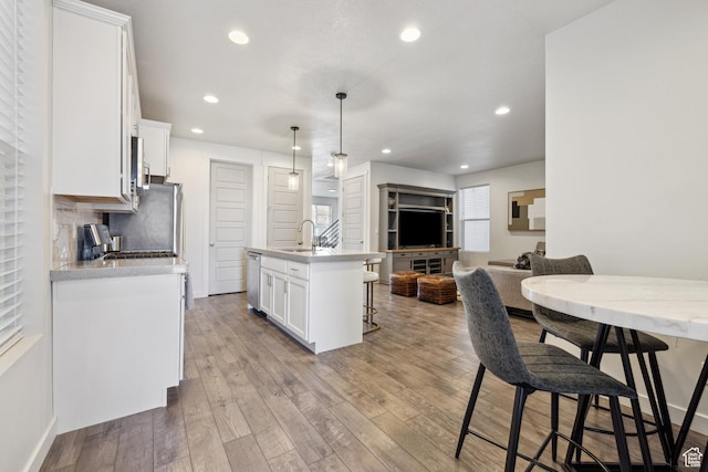 2344 N White Cliff Dr, Lehi, UT 84043 - kitchen with a breakfast bar area, light wood finished floors, tasteful backsplash, stainless steel dishwasher, and white cabinetry