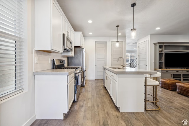 2344 N White Cliff Dr, Lehi, UT 84043 - kitchen featuring a breakfast bar area, decorative backsplash, appliances with stainless steel finishes, a sink, and hardwood / wood-style flooring