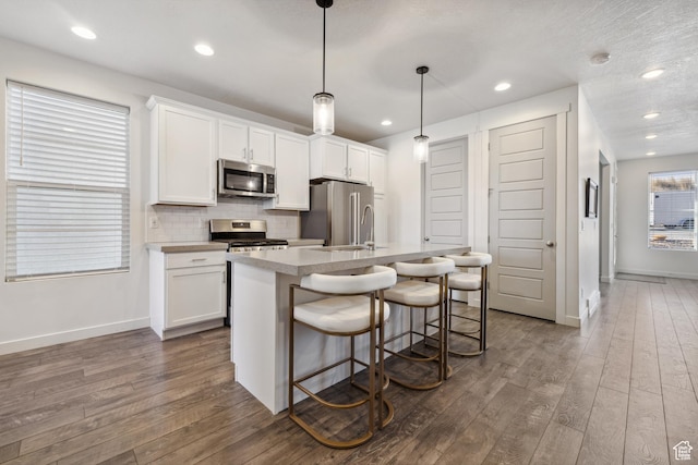 2344 N White Cliff Dr, Lehi, UT 84043 - kitchen with appliances with stainless steel finishes, dark wood-type flooring, an island with sink, and tasteful backsplash