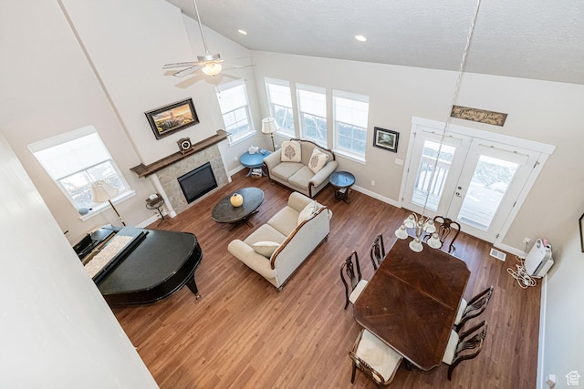 1206 W Holt Farm Ln, South Jordan, UT 84095 - living room featuring wood-type flooring, ceiling fan, a tiled fireplace, a textured ceiling, and high vaulted ceiling