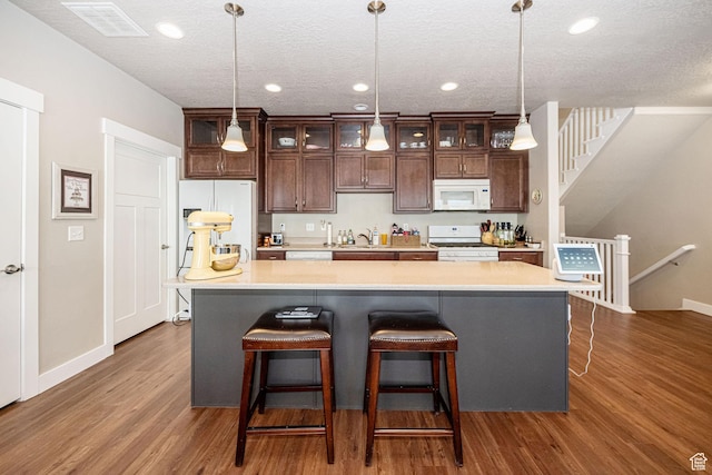 1206 W Holt Farm Ln, South Jordan, UT 84095 - kitchen with dark brown cabinets, decorative light fixtures, white appliances, and an island with sink