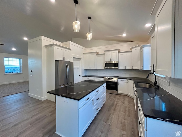 kitchen with sink, stainless steel appliances, a kitchen island, and white cabinets