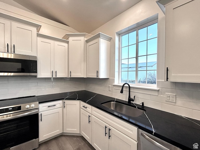 kitchen with sink, white cabinetry, backsplash, and stainless steel appliances