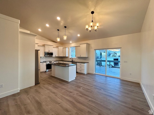 kitchen with hanging light fixtures, appliances with stainless steel finishes, sink, white cabinetry, and a kitchen island