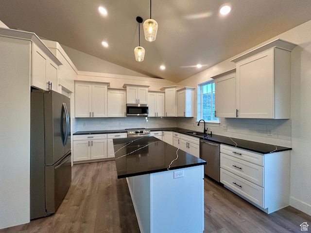 kitchen with white cabinets, stainless steel appliances, a kitchen island, and decorative light fixtures