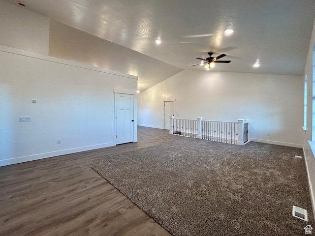 empty room featuring dark wood-type flooring, vaulted ceiling, and ceiling fan