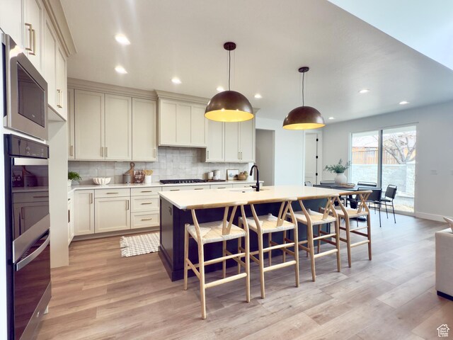 2946 N 1080 W, Lehi, UT 84043 - kitchen with decorative backsplash, a breakfast bar, a center island with sink, light countertops, and light wood finished floors