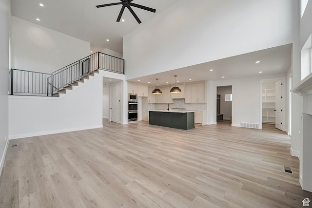 2946 N 1080 W, Lehi, UT 84043 - unfurnished living room featuring a towering ceiling, a ceiling fan, stairs, and visible vents