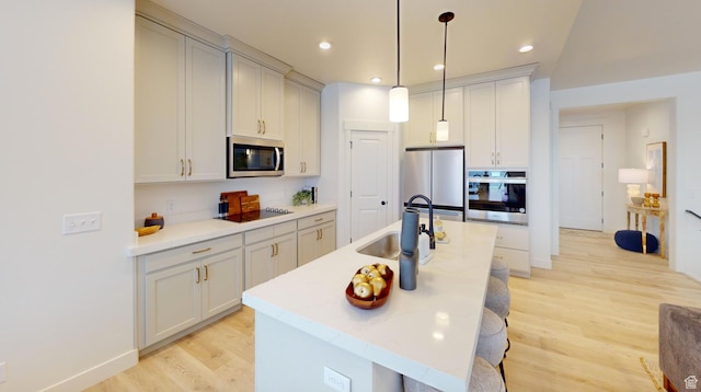 1502 S 380 E Unit 54, Salem, UT 84653 - kitchen featuring appliances with stainless steel finishes, light wood finished floors, a sink, a center island with sink, and pendant lighting