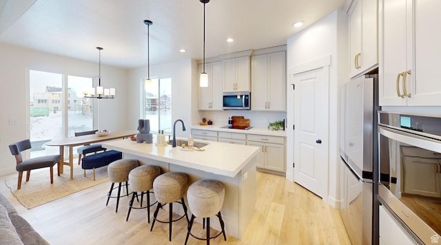 1502 S 380 E Unit 54, Salem, UT 84653 - kitchen featuring stainless steel appliances, a sink, light wood-style flooring, a breakfast bar, and a center island with sink