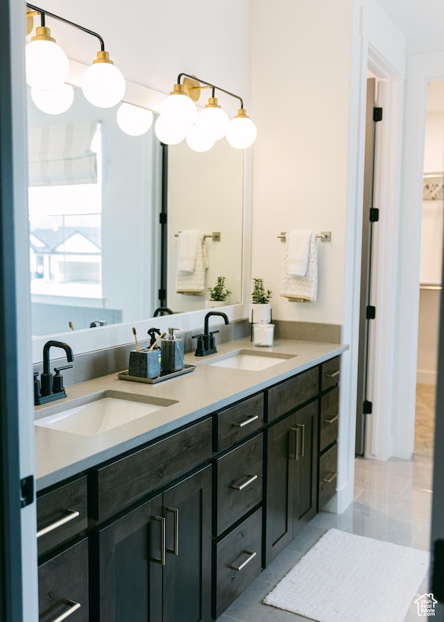 full bath featuring a walk in closet, double vanity, tile patterned floors, and a sink