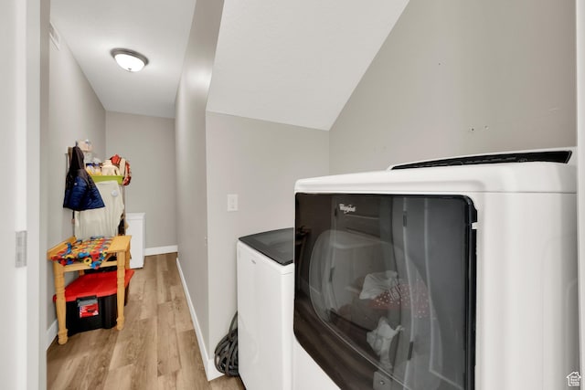 laundry room with washing machine and dryer and light hardwood / wood-style floors