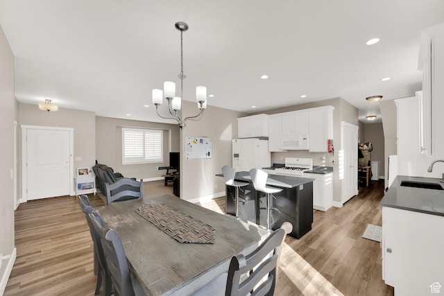 dining area with sink, light hardwood / wood-style flooring, and an inviting chandelier