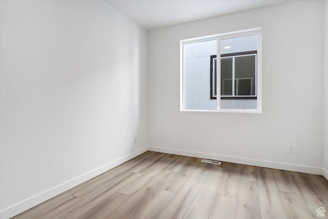 spare room featuring baseboards, visible vents, and wood finished floors