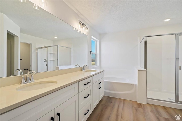 full bath with a textured ceiling, wood finished floors, a shower stall, and a sink