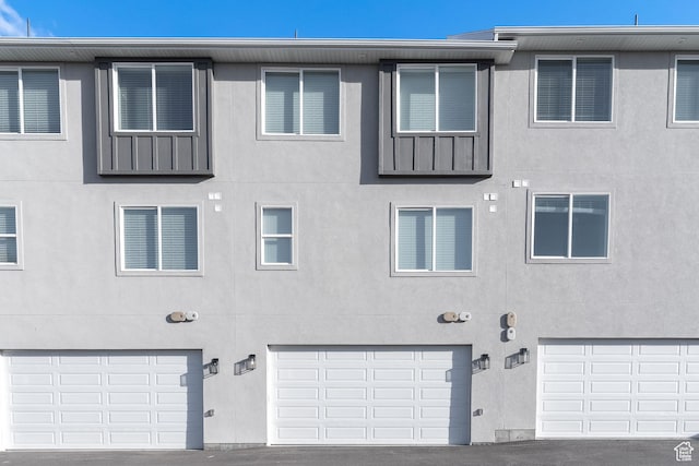 view of front facade featuring stucco siding, board and batten siding, and a garage