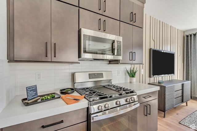 kitchen featuring light hardwood / wood-style floors, backsplash, and appliances with stainless steel finishes
