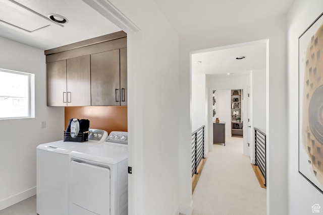 washroom with light carpet, cabinets, and washer and dryer