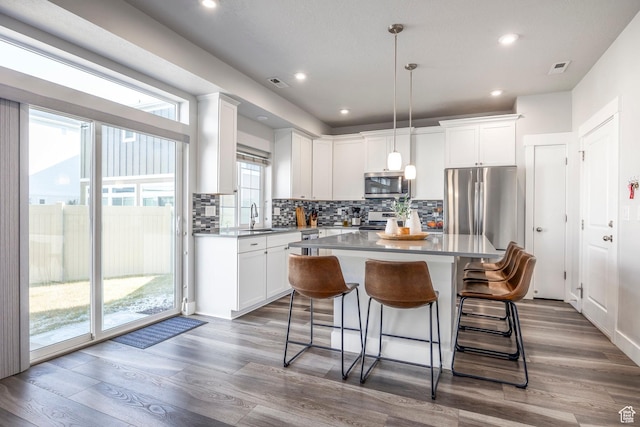 kitchen featuring visible vents, decorative backsplash, dark wood finished floors, appliances with stainless steel finishes, and a sink
