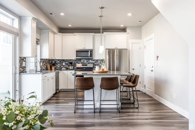 kitchen with stainless steel appliances, white cabinetry, a kitchen breakfast bar, and tasteful backsplash