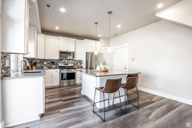kitchen featuring a breakfast bar, stainless steel appliances, backsplash, a sink, and a kitchen island