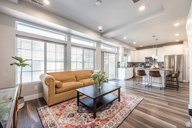 living room featuring recessed lighting, visible vents, baseboards, and wood finished floors
