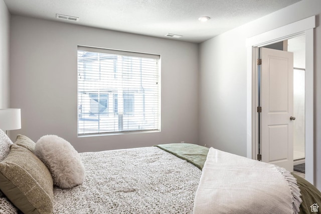 bedroom with a textured ceiling, multiple windows, and visible vents