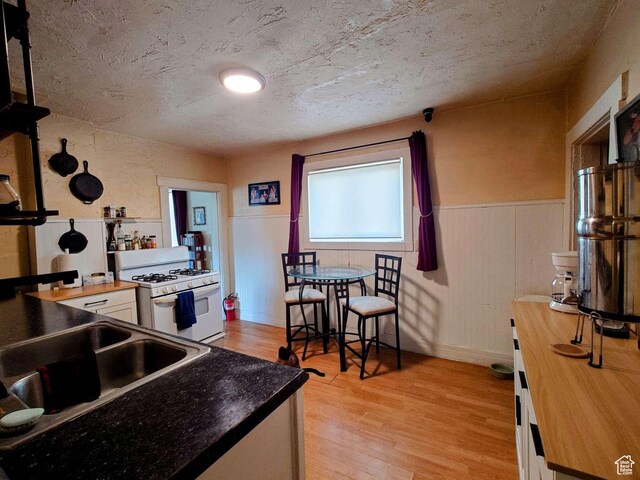 3260 Ogden Ave, Ogden, UT 84401 - kitchen featuring white gas stove, a textured ceiling, white cabinetry, light hardwood / wood-style flooring, and butcher block countertops