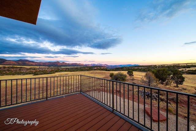 deck at dusk with a mountain view and a rural view