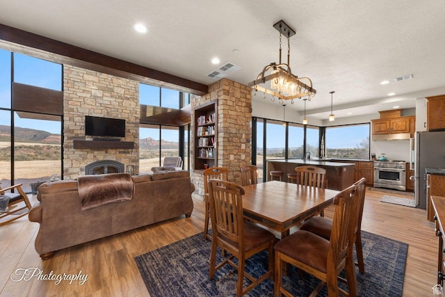 dining space with a fireplace, light hardwood / wood-style floors, a textured ceiling, and plenty of natural light