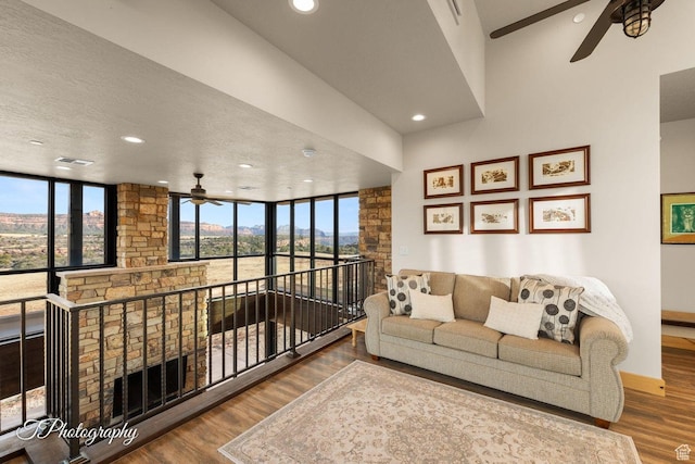 living room with ceiling fan, a textured ceiling, and wood-type flooring