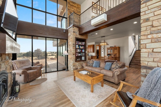 living room with hardwood / wood-style flooring, a wall mounted AC, and a towering ceiling