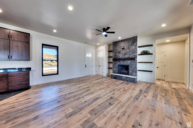 unfurnished living room featuring ceiling fan, light hardwood / wood-style floors, and a fireplace