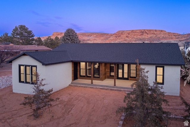 back house at dusk with a mountain view and a patio