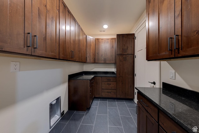 kitchen with dark tile patterned flooring and dark stone countertops