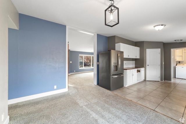 112 Arbor Dr, Moab, UT 84532 - kitchen with washer / dryer, stainless steel fridge, white cabinets, decorative light fixtures, and light tile patterned flooring