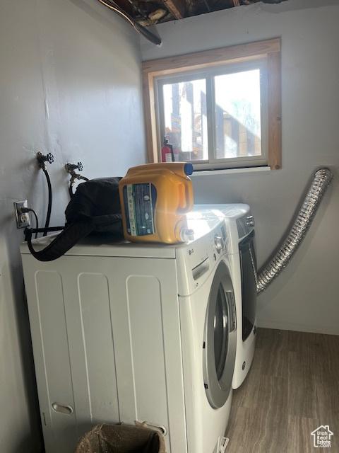 washroom with hardwood / wood-style floors and washing machine and clothes dryer