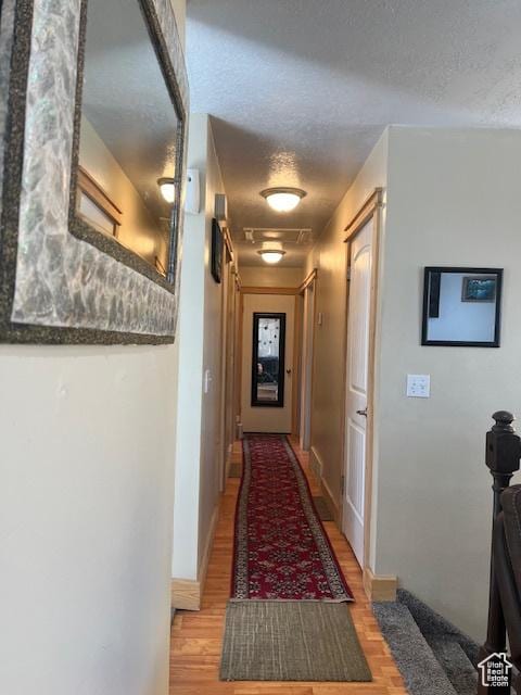 corridor featuring light wood-type flooring and a textured ceiling