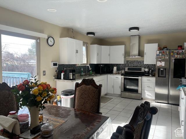 kitchen featuring white cabinets, sink, backsplash, stainless steel appliances, and wall chimney exhaust hood