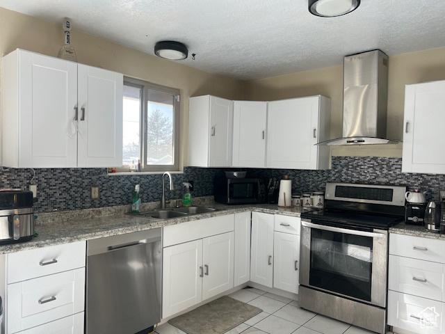 kitchen featuring white cabinets, wall chimney range hood, and appliances with stainless steel finishes