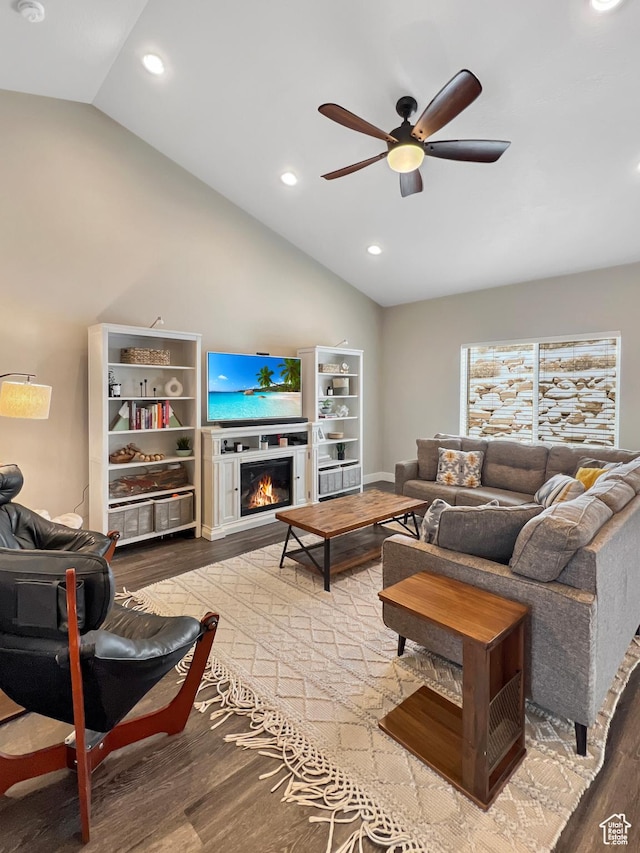 living area featuring a warm lit fireplace, recessed lighting, wood finished floors, a ceiling fan, and vaulted ceiling
