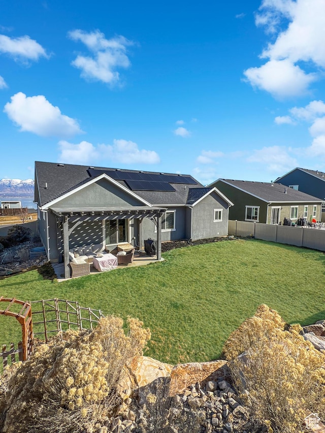 back of property featuring a patio, a fenced backyard, an outdoor living space, a lawn, and roof mounted solar panels