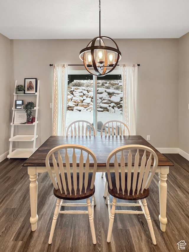 dining area with dark wood finished floors, baseboards, and an inviting chandelier