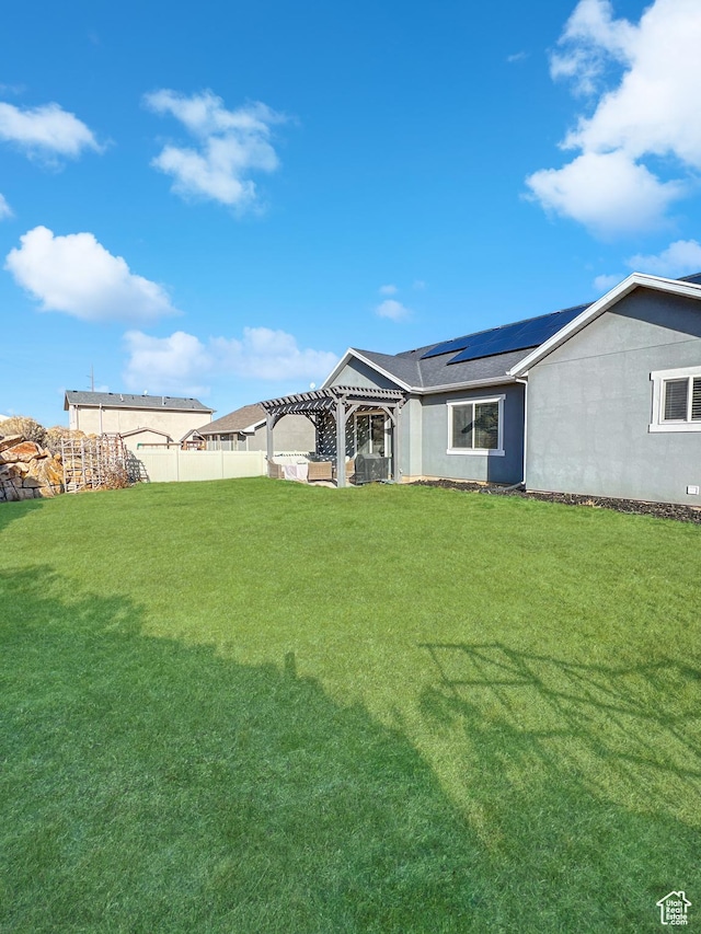 back of property featuring a yard, solar panels, fence, and a pergola