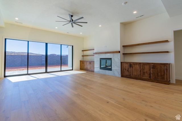 unfurnished living room featuring light hardwood / wood-style floors, a tile fireplace, and ceiling fan