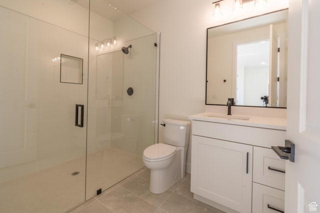 bathroom with vanity, toilet, tile patterned floors, and a shower with door