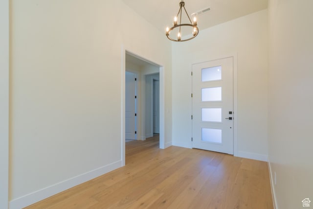 foyer entrance with light hardwood / wood-style flooring and an inviting chandelier
