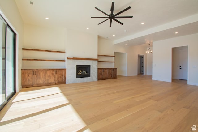 unfurnished living room with a tiled fireplace, light hardwood / wood-style floors, and ceiling fan