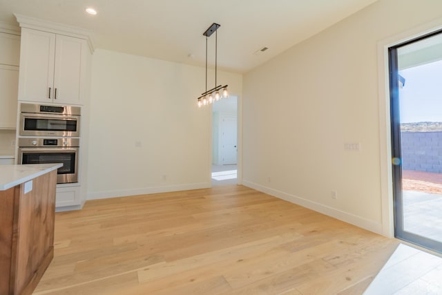 kitchen featuring white cabinetry, stainless steel double oven, pendant lighting, and plenty of natural light
