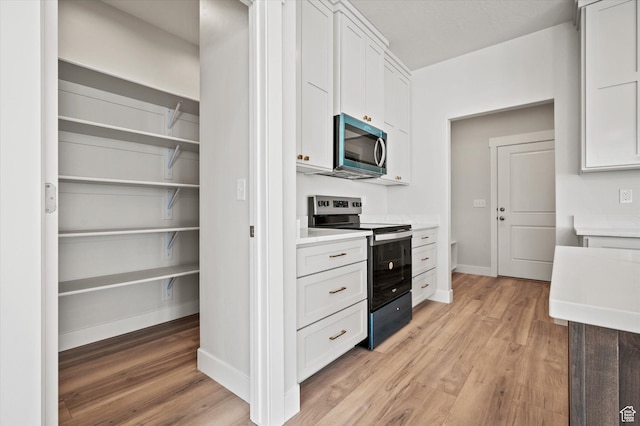 354 S 1150 E Unit 605, Smithfield, UT 84335 - kitchen with light wood finished floors, baseboards, white cabinetry, light countertops, and appliances with stainless steel finishes